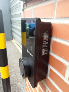 Socketed electric vehicle charger mounted on a brick wall